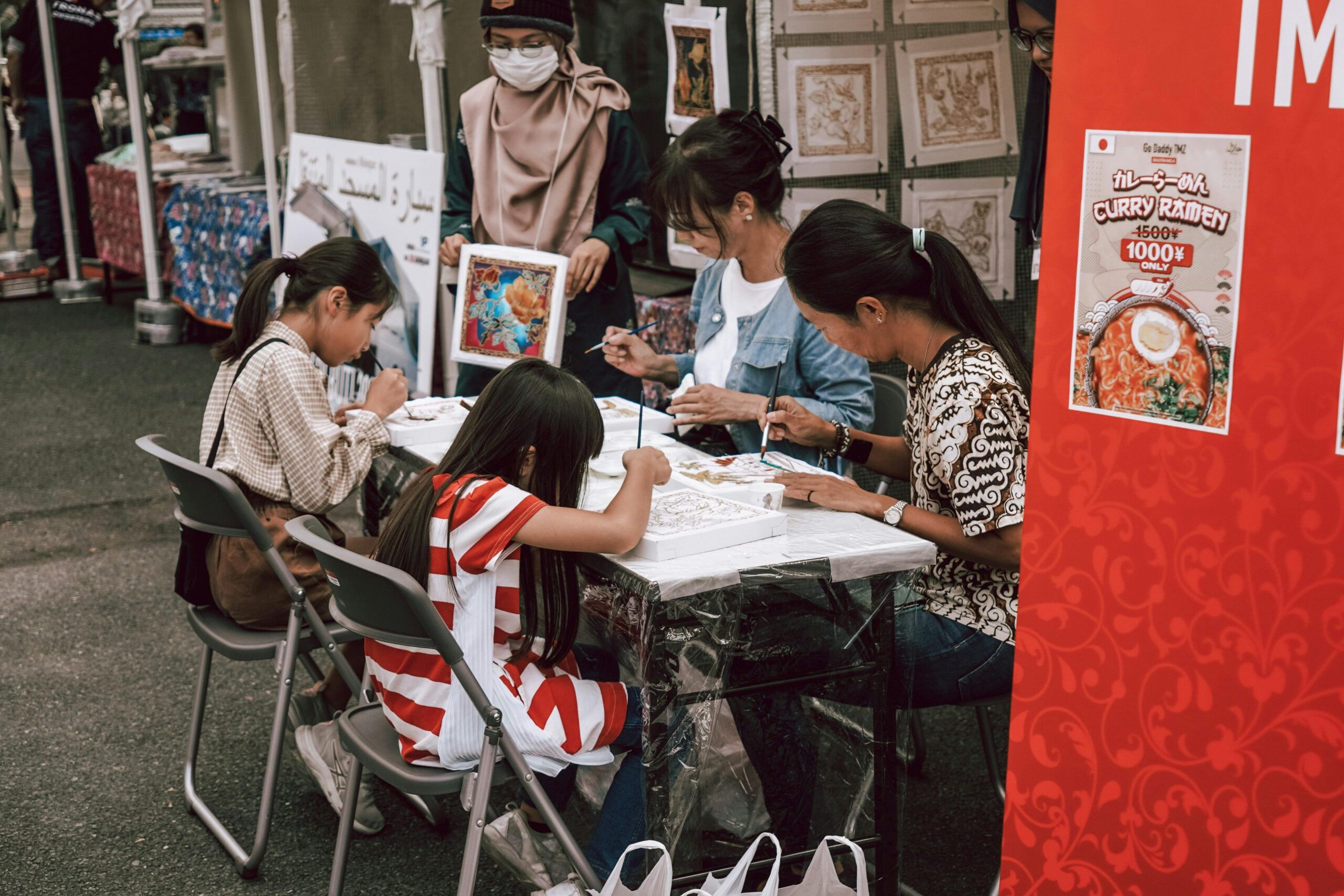 Family creating artwork together at an outdoor market. Engaging community event with children painting.